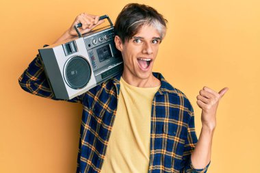 Kasetçalar tutan genç İspanyol adam, müzik dinliyor, başparmağını yana kaldırıyor, gülümsüyor ve ağzı açık. 