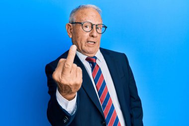 Senior caucasian man wearing business suit and tie showing middle finger, impolite and rude fuck off expression 