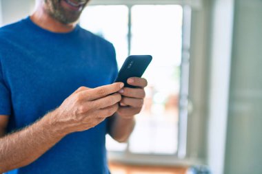 Genç İrlandalı adam mutlu bir şekilde gülümsüyor ve akıllı telefon kullanıyor..