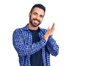 Latin asıllı genç adam, günlük kıyafetler giyip alkışlıyor ve mutlu, neşeli ve gururlu elleri bir arada alkışlıyor. 