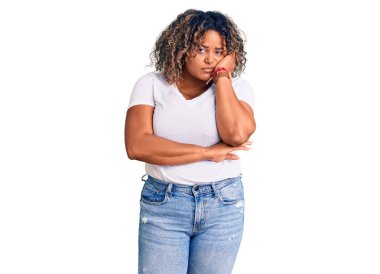 Genç Afro-Amerikan artı cüsseli kadın. Günlük kıyafetler giyiyor. Kollarını kavuşturup depresyondan sıkılmış ve yorgun görünüyor.. 