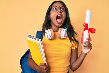 Sırt çantası taşıyan genç Hintli bir kız. Elinde diploma var. Öfkeli ve öfkeli çığlıklar atıyor.. 