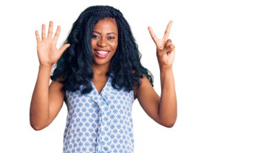 Güzel afro-amerikan kadın günlük yazlık tişört giyer ve yedinci parmaklarını göstererek gülümserken kendinden emin ve mutlu. 