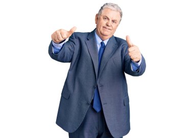 Kıdemli gri saçlı, iş ceketi giyen, elinde olumlu bir jest yapmayı onaylayan, gülümseyen ve başarı için mutlu bir adam. kazanan jest. 