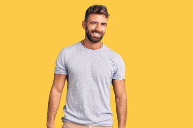 Gündelik kıyafetler giyen genç İspanyol adam kameraya seksi bir ifadeyle bakıyor, neşeli ve mutlu bir yüzle.. 