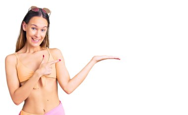 Bikini ve güneş gözlüğü takan güzel esmer kadın kameraya hayret ediyor ve gülümsüyor.. 