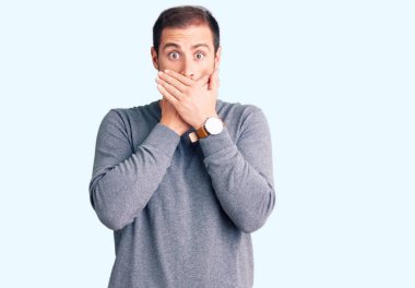 Sıradan bir kazak giyen yakışıklı beyaz adam yanlışlıkla elleri ile ağzını kapatırken şok oldu. gizli kavram. 