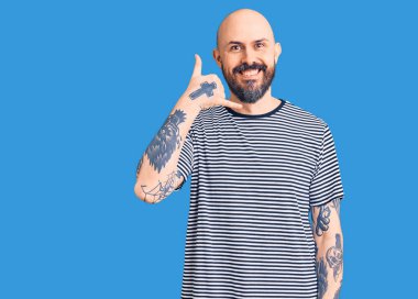 Genç, yakışıklı, sıradan kıyafetler giymiş, gülümseyen, el ve parmaklarıyla telefonla konuşan bir adam. iletişim kavramları. 