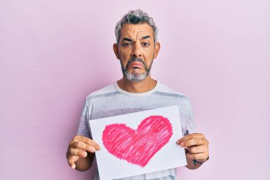 Orta yaşlı, kalbi olan gri saçlı bir adam sıkıntılı ve endişeli, sinirli ve korkmuş bir halde. hüzünlü ifade. 