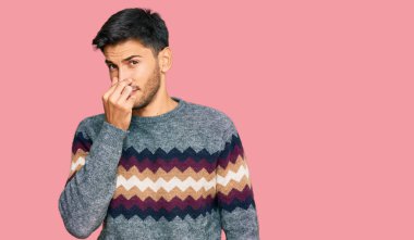 Kış süveteri giyen genç yakışıklı bir adam pis ve iğrenç bir koku alıyor. Nefesini burnunda tutuyor. Kötü kokuyor. 