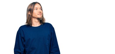 Uzun saçlı, sıradan bir kazak giyen yakışıklı beyaz adam gülümseyip yan tarafa bakıyor ve düşünüyor.. 