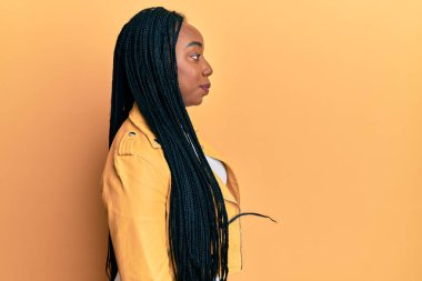 Genç Afrikalı Amerikalı kadın rahat bir görünüm takınıyor, rahat bir görünüm takınıyor kendine güvenen bir gülüşü var.. 