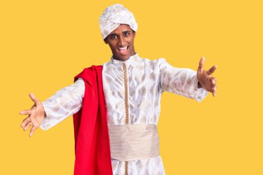 Geleneksel Sherwani elbisesi giyen Afrikalı yakışıklı adam kameraya sarılıp gülümsüyor. Mutluluğu kucaklayan neşeli bir ifade.. 