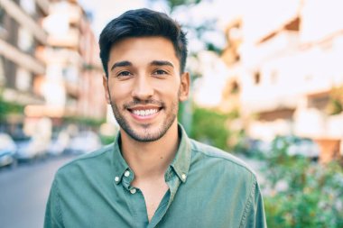 Genç Latin adam gülümseyerek şehirde mutlu mesut yürüyor..