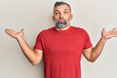 Orta yaşlı, sıradan kıyafetler giyen, kafası karışmış, kolları açık, hiçbir fikri olmayan ve şüpheli yüzlü bir adam.. 