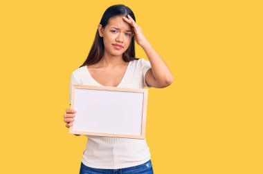 Elinde boş beyaz karatahta tutan genç ve güzel bir Latin kız. Elleri başının üstünde, şaşırmış ve kızgın bir yüzle stresli. 