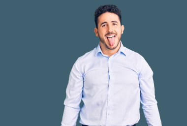 İş kıyafetleri giymiş genç İspanyol adam komik bir ifadeyle dilini dışarı çıkarıyor. duygu kavramı. 