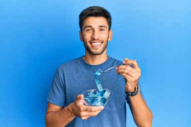 Kilo vermek için diyet yapan yakışıklı genç adam yüzünde mutlu ve havalı bir gülümsemeyle gülümsüyor. diş gösterme. 