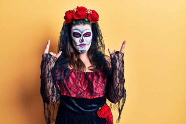 Sarı üzerine ölü kostümü giymiş genç bir kadın çılgın bir ifadeyle bağırıyor elleri havada rock sembolü yapıyor. Müzik yıldızı. ağır kavram. 