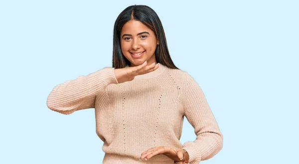 大きなと大規模なサインを示す手でジェスチャーウールの冬のセーターを着て若いラテン語の女の子は シンボルを測定します カメラを見て笑ってる 概念を測定し — ストック写真