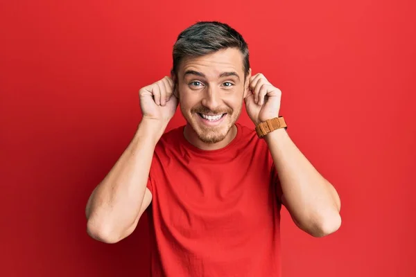 Bonito Caucasiano Vestindo Camiseta Vermelha Casual Sorrindo Puxando Orelhas Com — Fotografia de Stock