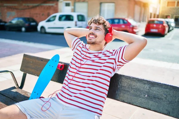 Νεαρός Καυκάσιος Σκέιτερ Χαμογελάει Ευτυχισμένος Καθισμένος Στον Πάγκο Ακούγοντας Μουσική — Φωτογραφία Αρχείου