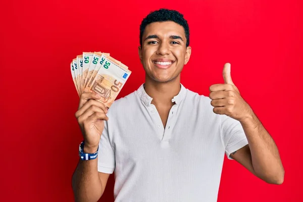 Hombre Árabe Joven Sosteniendo Billetes Euros Sonriendo Feliz Positivo Pulgar —  Fotos de Stock