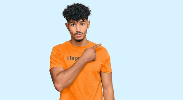 深刻かつ穏やかな顔を示す側に手指で指す幸福の言葉のメッセージとTシャツを着て若いアラブ人男性 — ストック写真