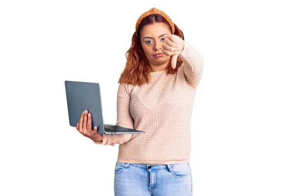 年轻的拉丁女人 手里拿着手提电脑 满脸怒容 负面迹象显示她不喜欢大拇指朝下 拒绝的概念 — 图库照片