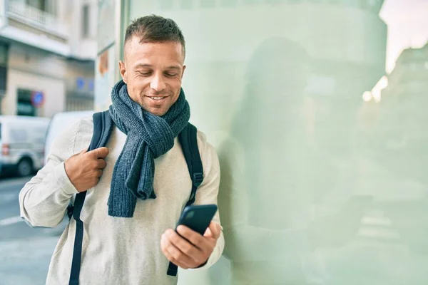 Young caucasian student man smiling happy using smartphone at the city.