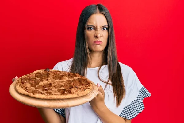 Jovem Hispânica Segurando Pizza Italiana Cético Nervoso Franzindo Testa Chateado — Fotografia de Stock