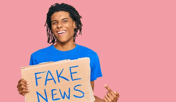 Joven Hombre Afroamericano Sosteniendo Pancarta Noticias Falsas Sonriendo Feliz Señalando —  Fotos de Stock