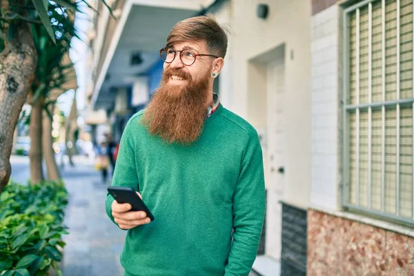 Joven Irlandés Con Barba Pelirroja Sonriendo Feliz Usando Smartphone Ciudad — Foto de Stock