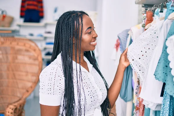 若いアフリカ系アメリカ人女性が衣料品店で幸せな持株服を笑っている — ストック写真