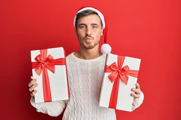 Knappe Blanke Man Met Kerstmuts Cadeautjes Kijkend Naar Camera Die — Stockfoto