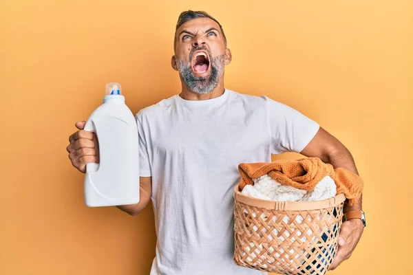 Middelbare Leeftijd Knappe Man Met Wasmand Wasmiddel Fles Boos Gek — Stockfoto