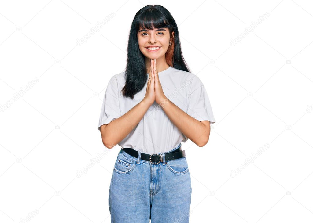 Young hispanic girl wearing casual clothes praying with hands together asking for forgiveness smiling confident. 