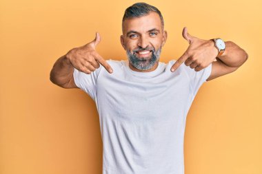 Orta yaşlı, beyaz tişört giyen, kendine güvenen, gülümseyen, kendini gururlu ve mutlu gösteren yakışıklı bir adam.. 