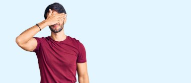 Yakışıklı İspanyol bir adam, günlük kıyafetler giyiyor, gözlerini eliyle kapatıyor, ciddi ve üzgün görünüyor. Görme, saklama ve reddetme konsepti 