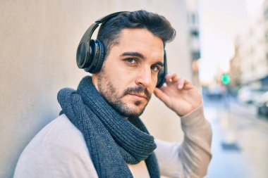 Gevşek yüzlü, şehirde kulaklık takıp müzik dinleyen genç bir İspanyol..