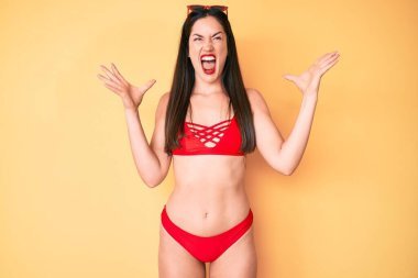 Bikini giyen, deli gibi bağıran, bağıran, saldırgan ifadeler takınıp kollarını kaldıran beyaz bir kadın. hüsran kavramı. 