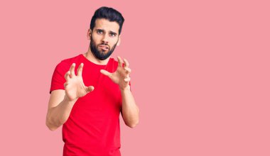 Sakallı, sıradan bir tişört giyen, tiksindirici ve tiksindirici bir ifade takınan genç yakışıklı bir adam. Çünkü tiksinti tepkisi veriyor. Eller havada. 