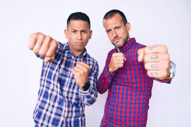 Genç eşcinsel iki adam gündelik kıyafetler giyip dövüşmek için yumruklarını yumrukluyor, agresif ve öfkeli saldırı, tehdit ve şiddet. 