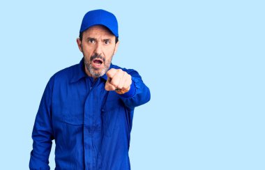 Orta yaşlı, tamirci üniforması giyen yakışıklı bir adam kameraya kızgın ve sinirli olduğunu gösteriyor. 