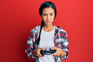 Güzel İspanyol kadın video oyunu oynuyor. Kontrolcü, şüpheci ve gergin. Sorun yüzünden surat asıyor. negatif kişi. 