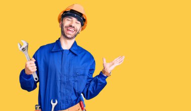 Elektrikçi üniforması giyen genç İspanyol adam zaferi mutlu bir gülümsemeyle kutluyor ve ellerini kaldırarak kazanan yüz ifadesi sergiliyor. 