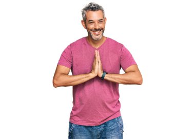 Orta yaşlı, gri saçlı, günlük kıyafetler giyen, elleriyle dua eden, affedilmek isteyen, kendinden emin, gülümseyen bir adam.. 