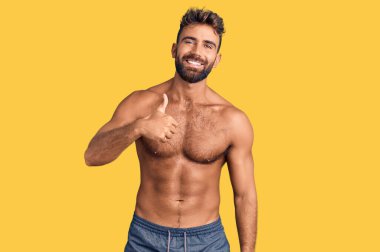 Mayo giyen genç İspanyol adam elinle mutlu bir jest yapıyor. Kameraya bakıp başarıyı gösteren ifade. 