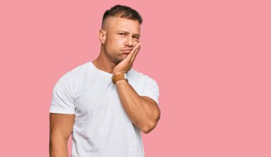 Yakışıklı, beyaz tişört giyen, yorgun görünen ve depresyondan sıkılmış kollarını kavuşturan kaslı adam.. 