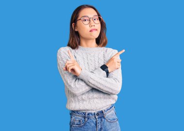 Gündelik giysiler giyen genç, güzel Çinli kız her iki tarafı da parmaklarıyla işaret ediyor, farklı yönlere. 